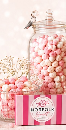Pink and white sweets in glass jars with Norfolk Sweet Company packaging